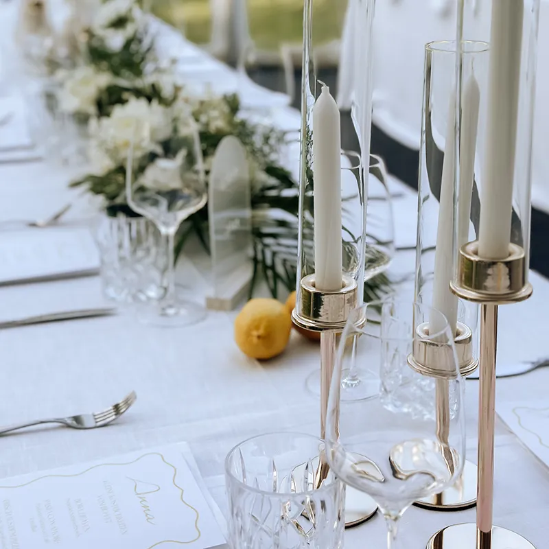 Silberne Kerzenhalter mit weißen Kerzen auf einer schön gedeckten Hochzeitstafel