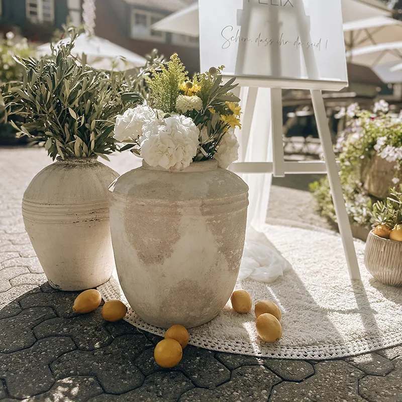 Große Bodenvasen mit weißen Blumen vor einer weißen Staffelei im Gegenlicht